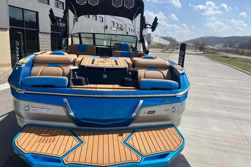 Slide: The Image of 2022 MasterCraft X26 boat with blue and tan interior, docked outdoors under a clear sky. - 9