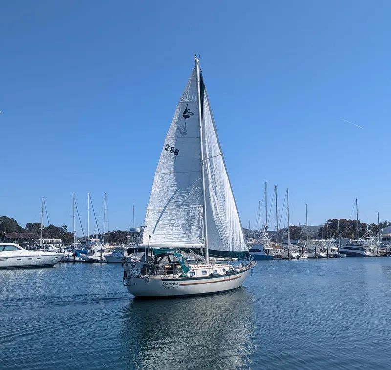 Slide: The Image of Sailboat Pacific Seacraft 34, 1995 model, sailing in a marina under clear blue skies. - 1