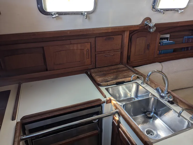 Slide: The Image of Interior of 1995 Pacific Seacraft 34 sailboat, featuring a wooden kitchen with a stainless steel sink. - 42