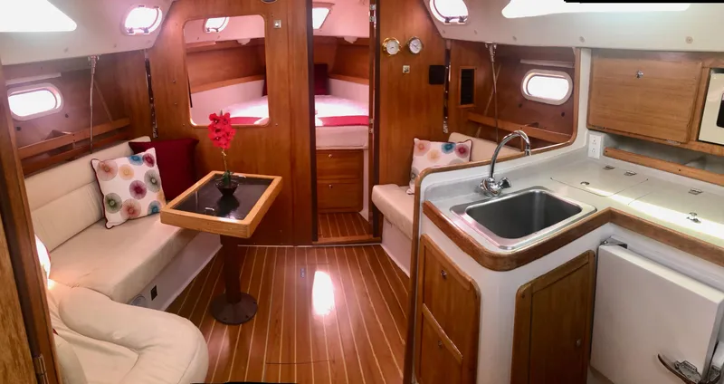 Slide: The Image of Interior of 2005 Catalina 310 sailboat with cozy seating, kitchenette, and wood finish. - 3