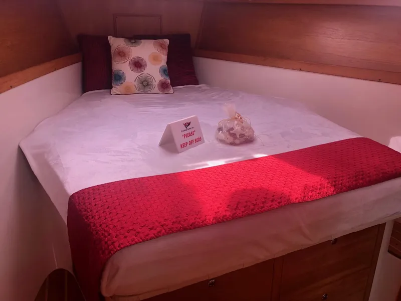 Slide: The Image of Cozy cabin bed in 2005 Catalina 310 sailboat with red accents and decorative pillows. - 4
