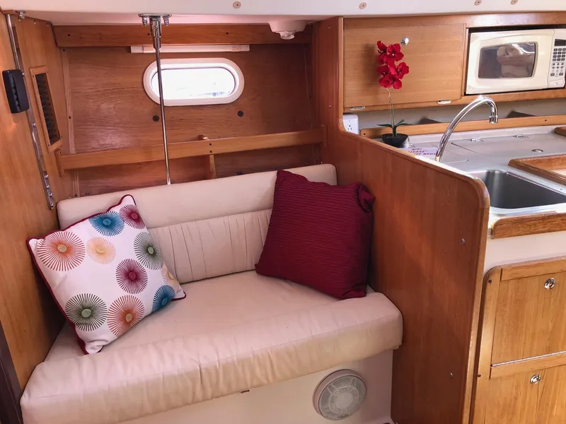 Slide: The Image of Cozy Catalina 310 yacht interior with cushions, kitchenette, and porthole, 2005 model. - 6