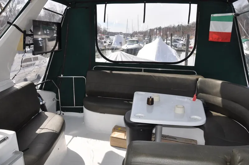 Slide: The Image of 2000 Carver 530 Voyager Pilothouse interior with seating, table, and marina view. - 12