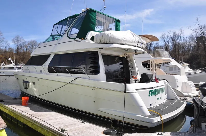 Slide: The Image of 2000 Carver 530 Voyager Pilothouse yacht docked at marina, featuring green canopy and spacious deck. - 7