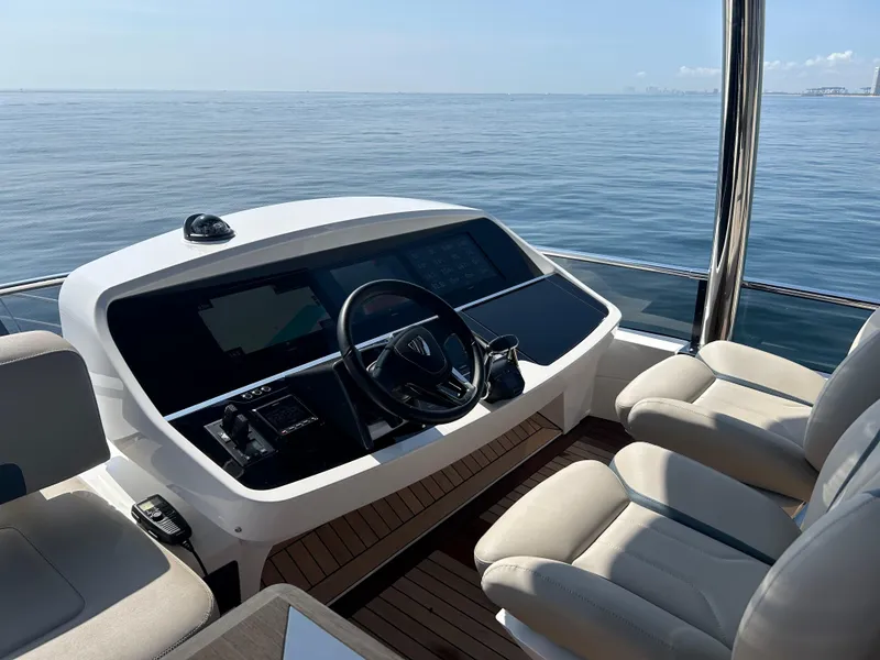 Slide: The Image of 2024 Fairline Squadron 68 yacht helm with ocean view, featuring modern controls and seating. - 22