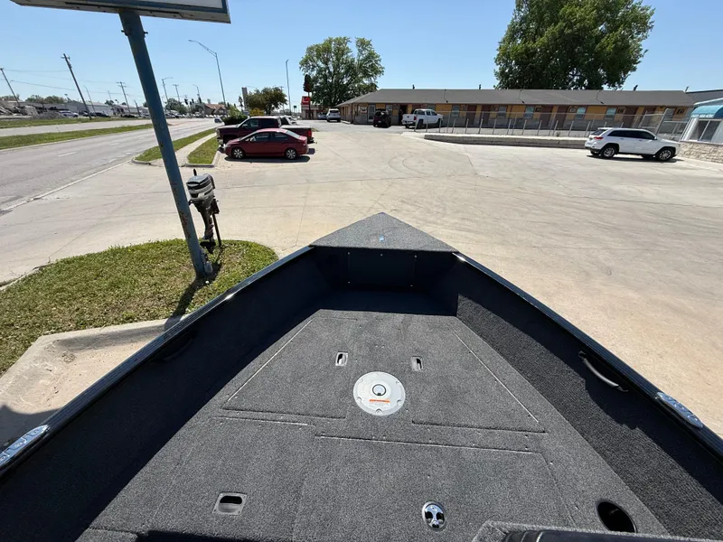 Slide: The Image of 2025 Lund 1650 Rebel XL SS boat parked in a lot, with cars and buildings nearby. - 6