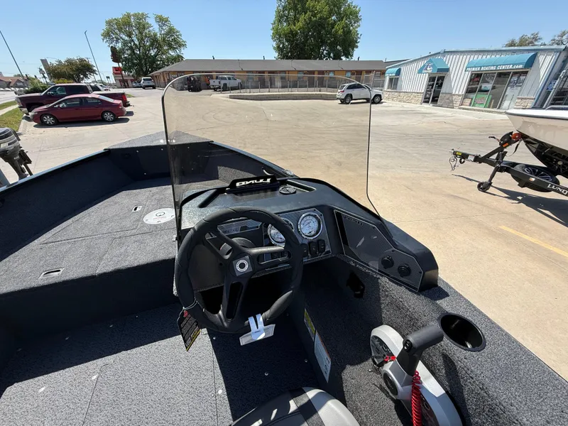 Slide: The Image of 2025 Lund 1650 Rebel XL SS boat interior with steering wheel and dashboard in a parking lot. - 8
