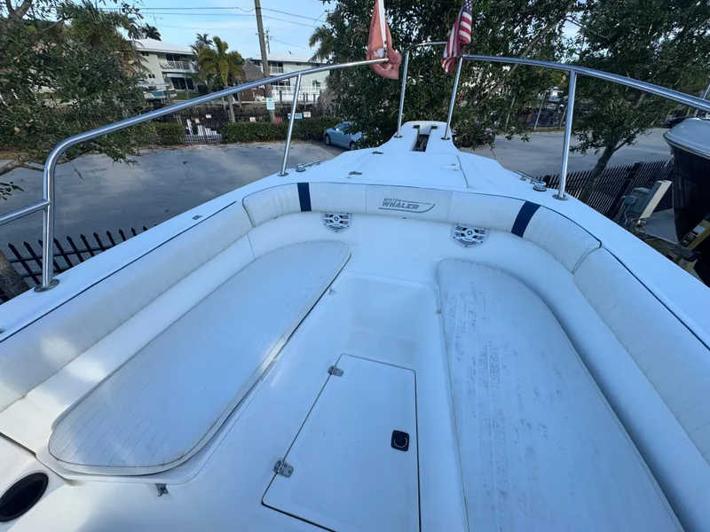 Slide: The Image of 2000 Boston Whaler 26 Outrage boat deck with seating and railings, docked outdoors. - 29