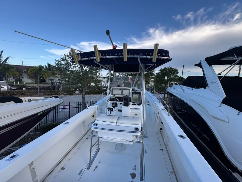 Slide: The Image of 2000 Boston Whaler 26 Outrage boat with center console and canopy, docked outdoors. - 3