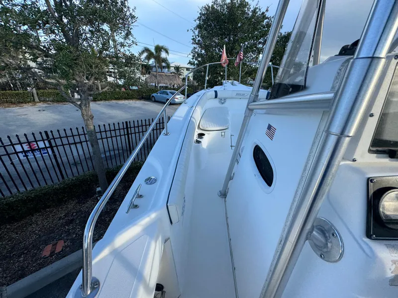 Slide: The Image of 2000 Boston Whaler 26 Outrage boat deck with railing, parked near trees and fence. - 40