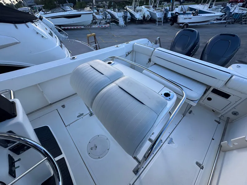 Slide: The Image of 2000 Boston Whaler 26 Outrage boat interior with seating and steering wheel, docked among other boats. - 5