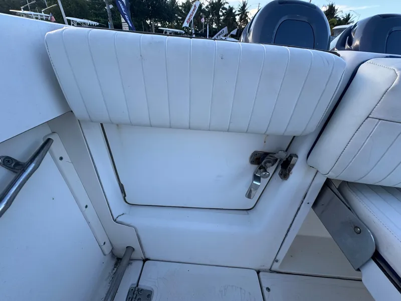 Slide: The Image of 2000 Boston Whaler 26 Outrage boat interior with white cushioned seating and storage compartment. - 54
