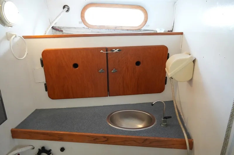 Slide: The Image of 1974 Morgan 33 Out Island yacht bathroom with sink, wooden cabinets, and porthole window. - 19