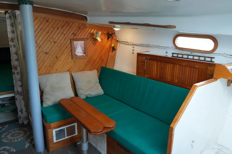 Slide: The Image of 1974 Morgan 33 Out Island interior with green seating, wooden accents, and nautical decor. - 21