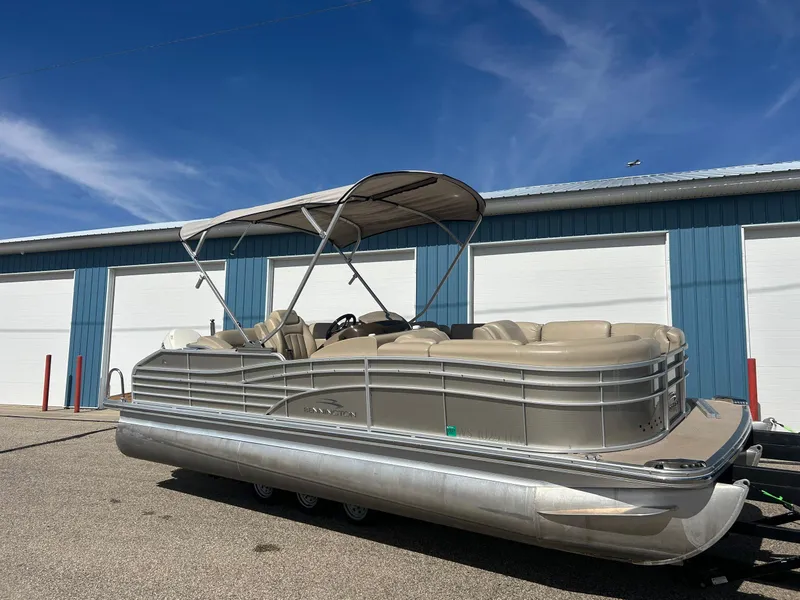 Slide: The Image of 2012 Bennington 2250RCL pontoon boat with canopy, parked outdoors under blue sky. - 3