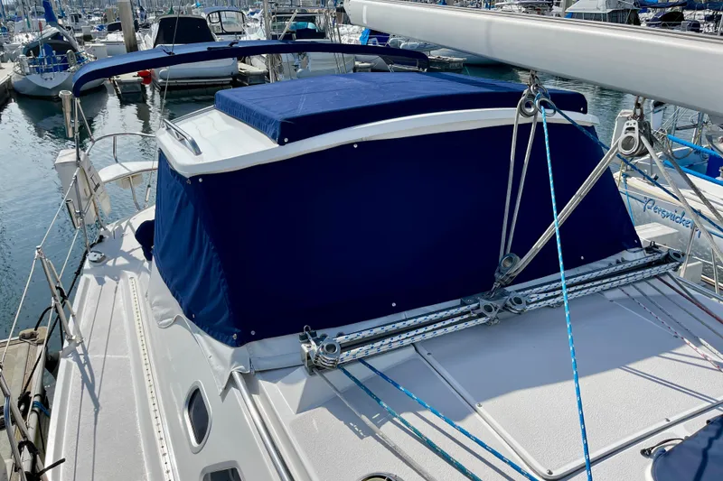 Slide: The Image of 2001 Catalina 380 sailboat with blue canvas cover docked in a marina. - 13