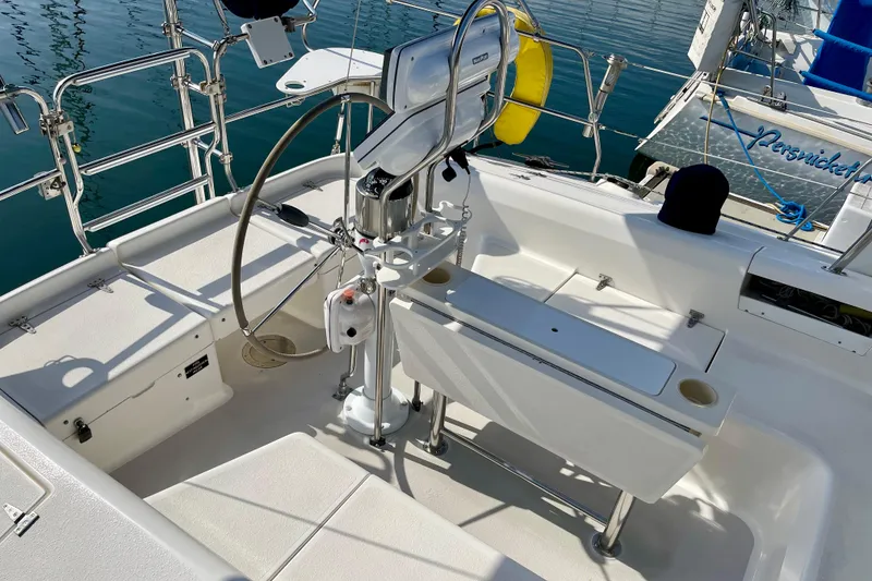 Slide: The Image of Cockpit of 2001 Catalina 380 sailboat with steering wheel and seating, docked on calm water. - 22