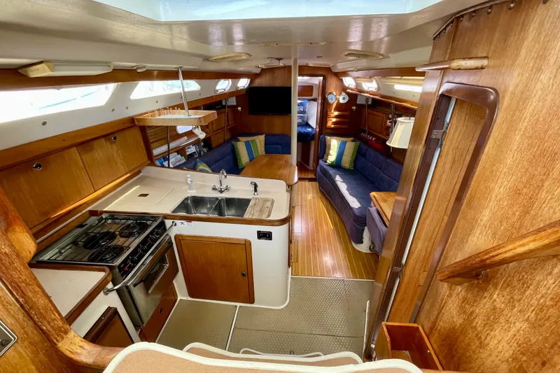 Slide: The Image of Interior of 2001 Catalina 380 sailboat with kitchen, seating, and wood finishes. - 27