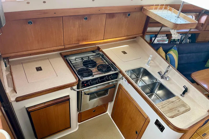 Slide: The Image of 2001 Catalina 380 yacht kitchen with stove, dual sink, and wooden cabinetry. - 28