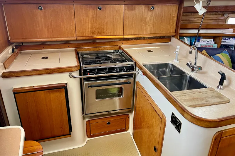 Slide: The Image of Compact kitchen in a 2001 Catalina 380 sailboat with stove, sink, and wooden cabinetry. - 29