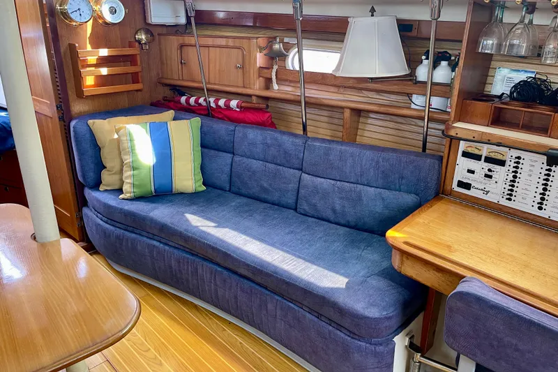 Slide: The Image of Interior of 2001 Catalina 380 sailboat with blue sofa, colorful pillows, and wooden furnishings. - 42