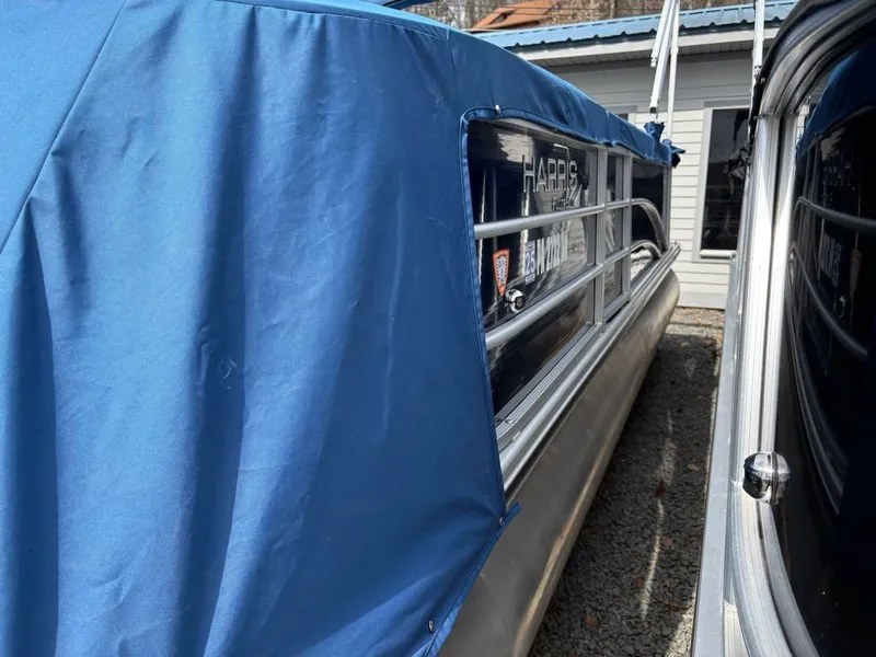 Slide: The Image of 2014 Harris Cruiser 220 pontoon boat with blue cover, parked outdoors. - 14