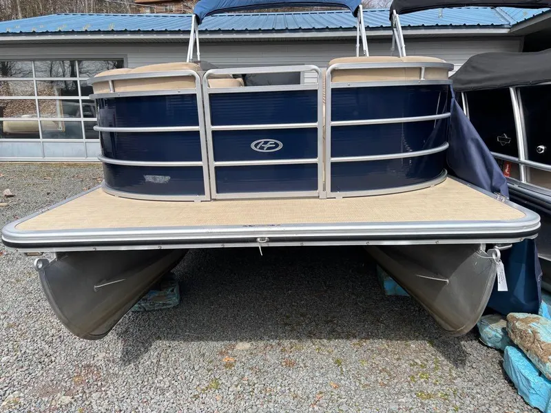 Slide: The Image of 2014 Harris Cruiser 220 pontoon boat with blue exterior, parked on gravel. - 9