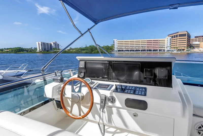 Slide: The Image of 2009 Uniesse 65 MY yacht helm with wooden steering wheel, overlooking waterfront buildings. - 23