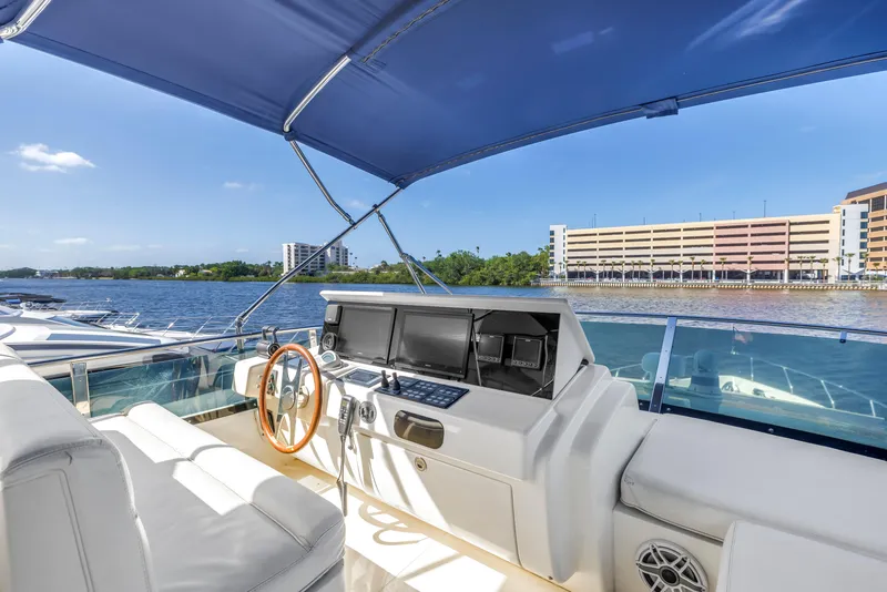 Slide: The Image of 2009 Uniesse 65 MY yacht helm with blue canopy, overlooking waterfront buildings. - 28