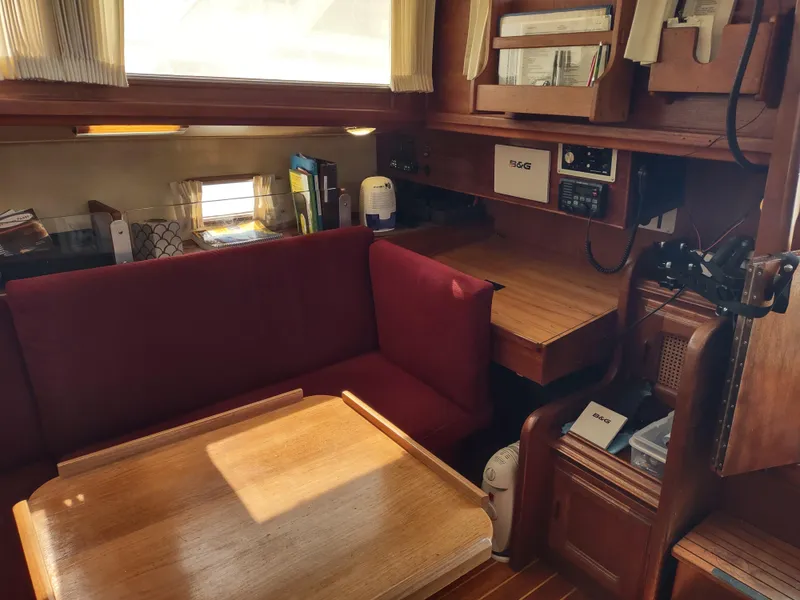 Slide: The Image of Interior of 1979 Islander Freeport 41 sailboat with red seating and wooden table. - 32