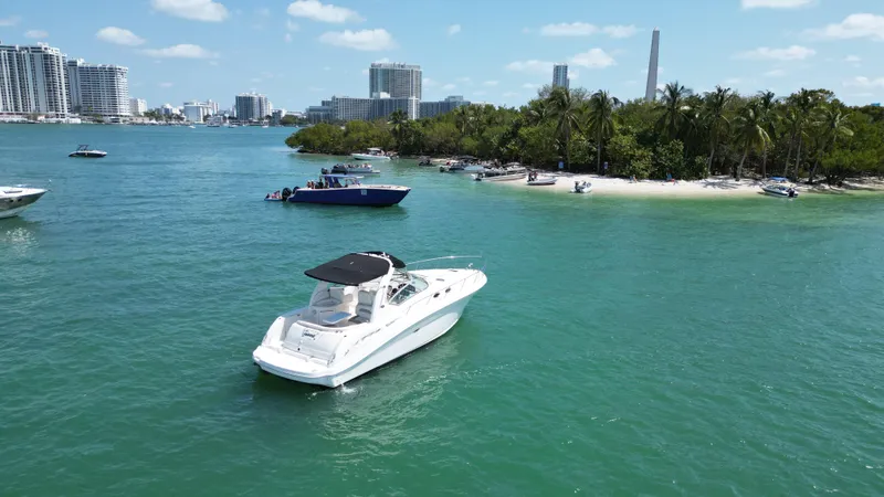 Slide: The Image of 2003 Sea Ray 340 Sundancer cruising near a tropical island with city skyline. - 10