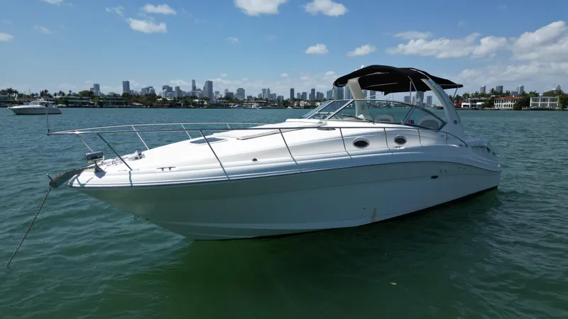 Slide: The Image of 2003 Sea Ray 340 Sundancer boat on calm water with city skyline in background. - 8