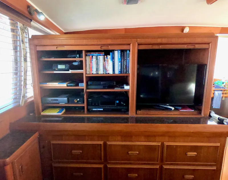 Slide: The Image of 1986 Bertram 46 Sportfisher interior with wooden cabinets, shelves, books, and a TV. - 21