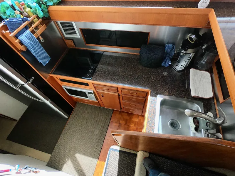Slide: The Image of 1986 Bertram 46 Sportfisher kitchen with stove, sink, and wooden cabinetry. - 25