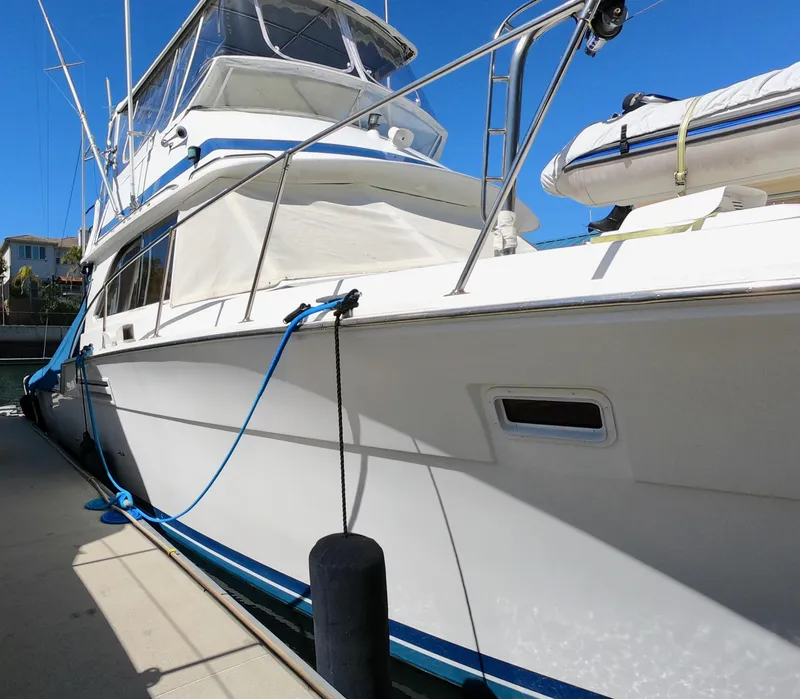 Slide: The Image of 1986 Bertram 46 Sportfisher yacht docked, featuring sleek white exterior and blue accents. - 3