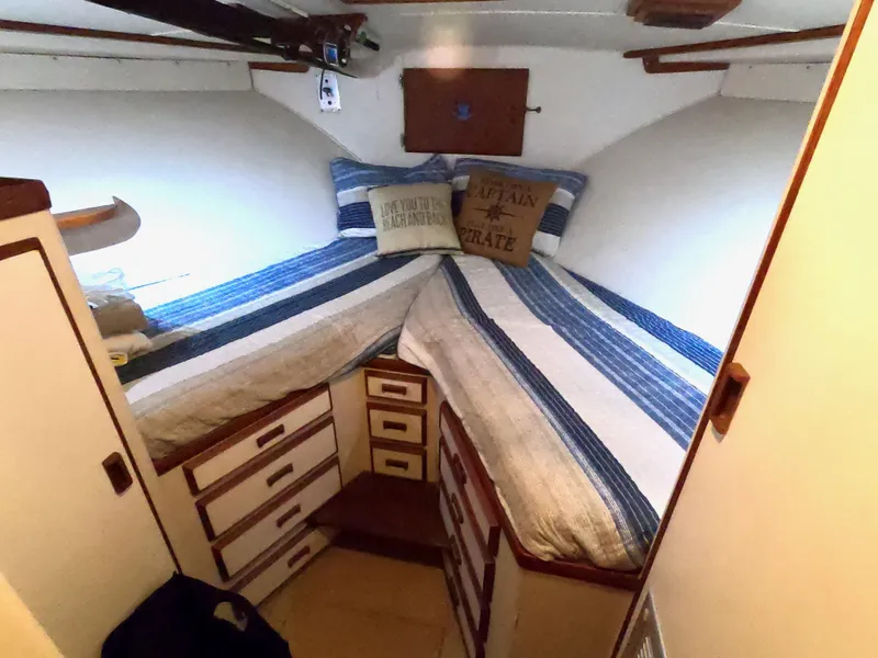 Slide: The Image of 1986 Bertram 46 Sportfisher cabin with striped bedding and storage drawers. - 33