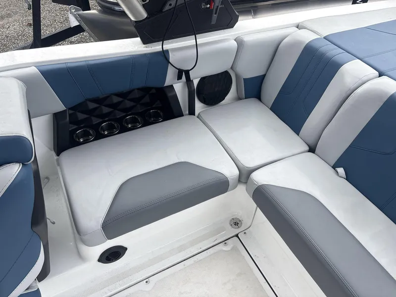 Slide: The Image of 2022 Malibu 21lx boat interior with blue and gray seating and cup holders. - 15
