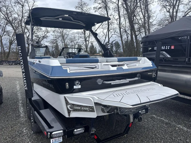 Slide: The Image of 2022 Malibu 21lx boat with blue and white design, parked outdoors on a trailer. - 3