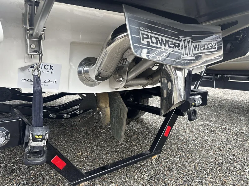 Slide: The Image of 2022 Malibu 21lx boat with Power Wedge III, rear view on gravel surface. - 4