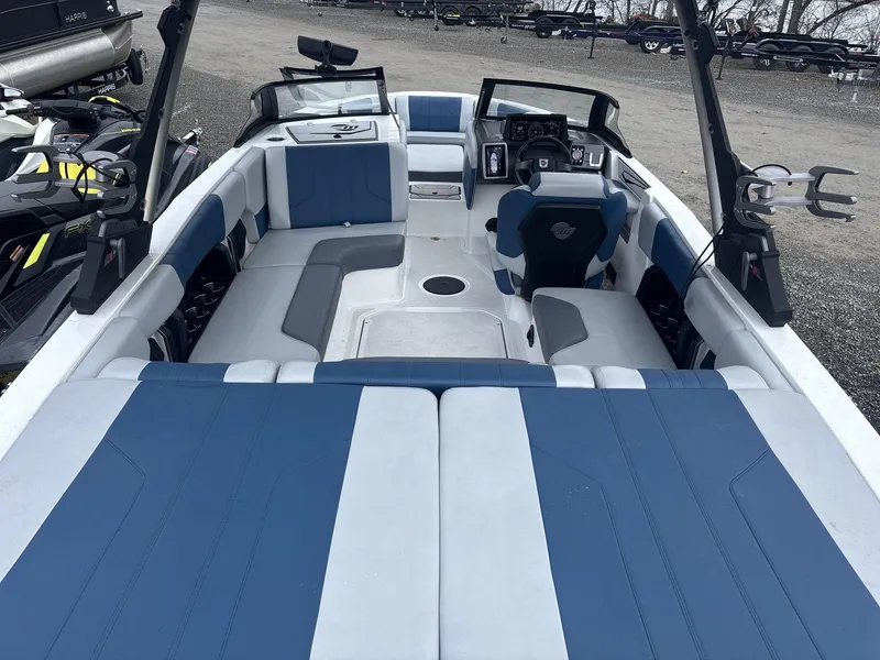 Slide: The Image of 2022 Malibu 21lx boat interior with blue and gray seating, dashboard, and wakeboard racks. - 5