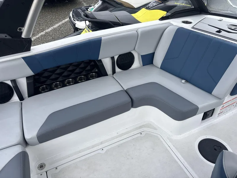 Slide: The Image of 2022 Malibu 21lx boat interior with blue and gray seating, cup holders, and sleek design. - 8