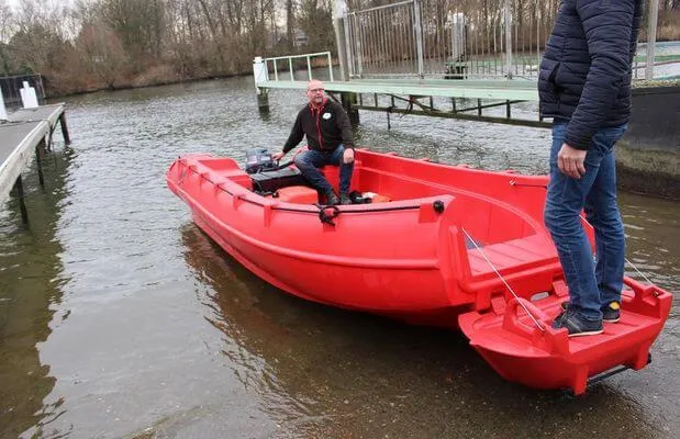 Slide: The Image of Red 2025 Whaly 500R Pro boat on water near dock, with two people aboard. - 10
