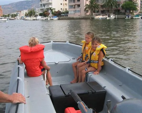Slide: The Image of Children wearing life jackets on a Whaly 370 boat, 2025, in a scenic waterway. - 7