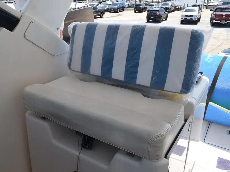 Slide: The Image of 2006 Tiara Yachts 3200 Open seating with striped cushion, docked with cars in background. - 23