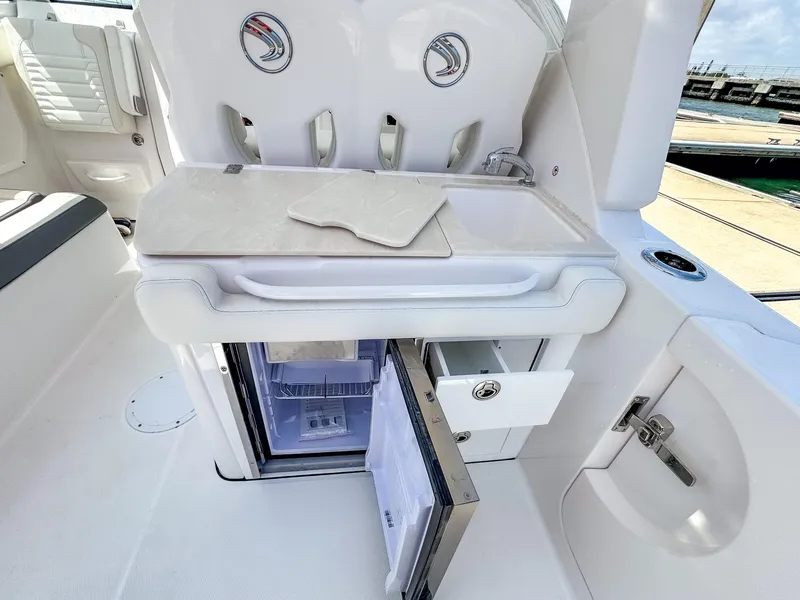 Slide: The Image of 2025 Edgewater 262 CX boat interior with open mini fridge and storage compartments. - 25