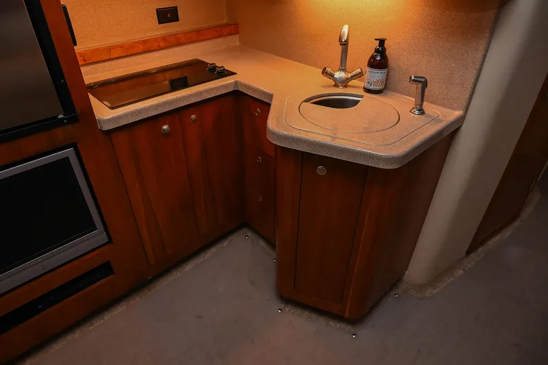 Slide: The Image of 2005 Cruisers Yachts 370 Express kitchen with stove, sink, and wooden cabinetry. - 33