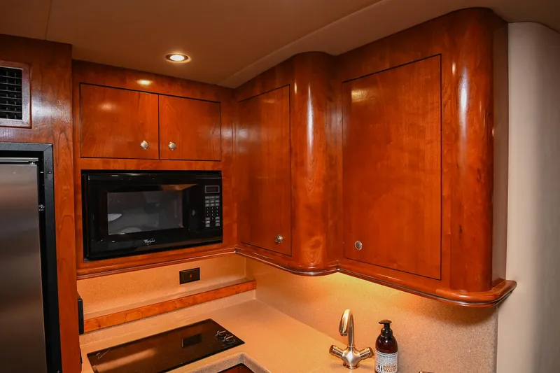 Slide: The Image of 2005 Cruisers Yachts 370 Express kitchen with wood cabinets, microwave, and sink. - 34