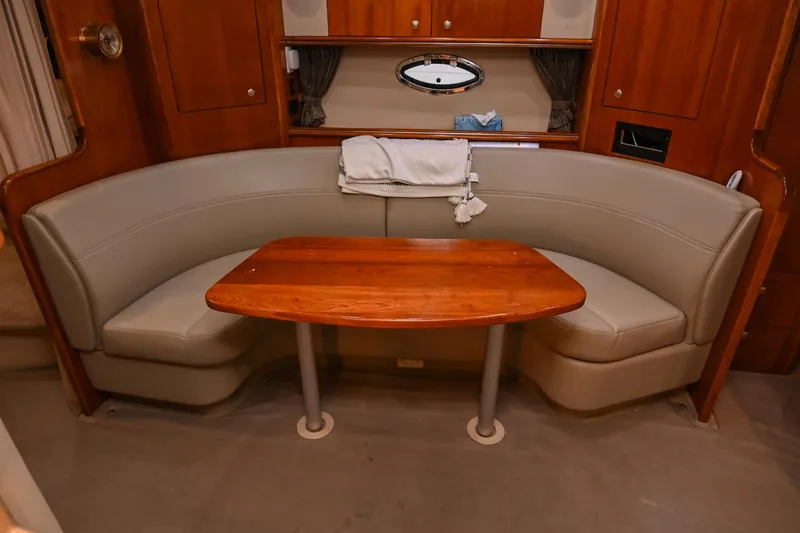Slide: The Image of 2005 Cruisers Yachts 370 Express interior with curved seating and wooden table. - 38