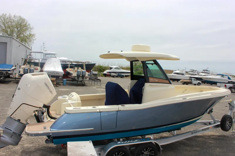Slide: The Image of 2024 Chris-Craft Catalina 24 boat on trailer, blue hull, outboard motor, marina background. - 5