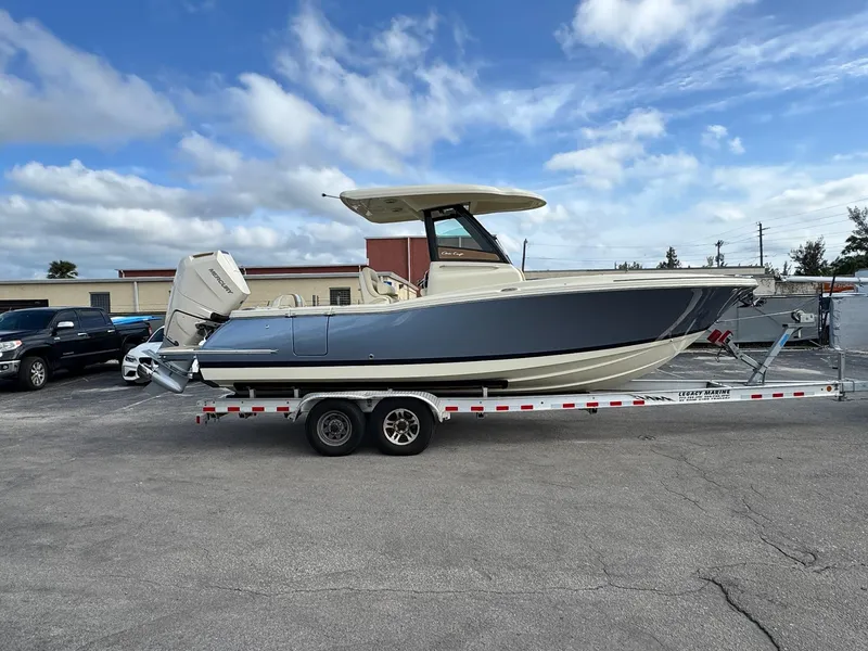 Slide: The Image of 2024 Chris-Craft Catalina 24 boat on trailer, parked outdoors under a partly cloudy sky. - 55